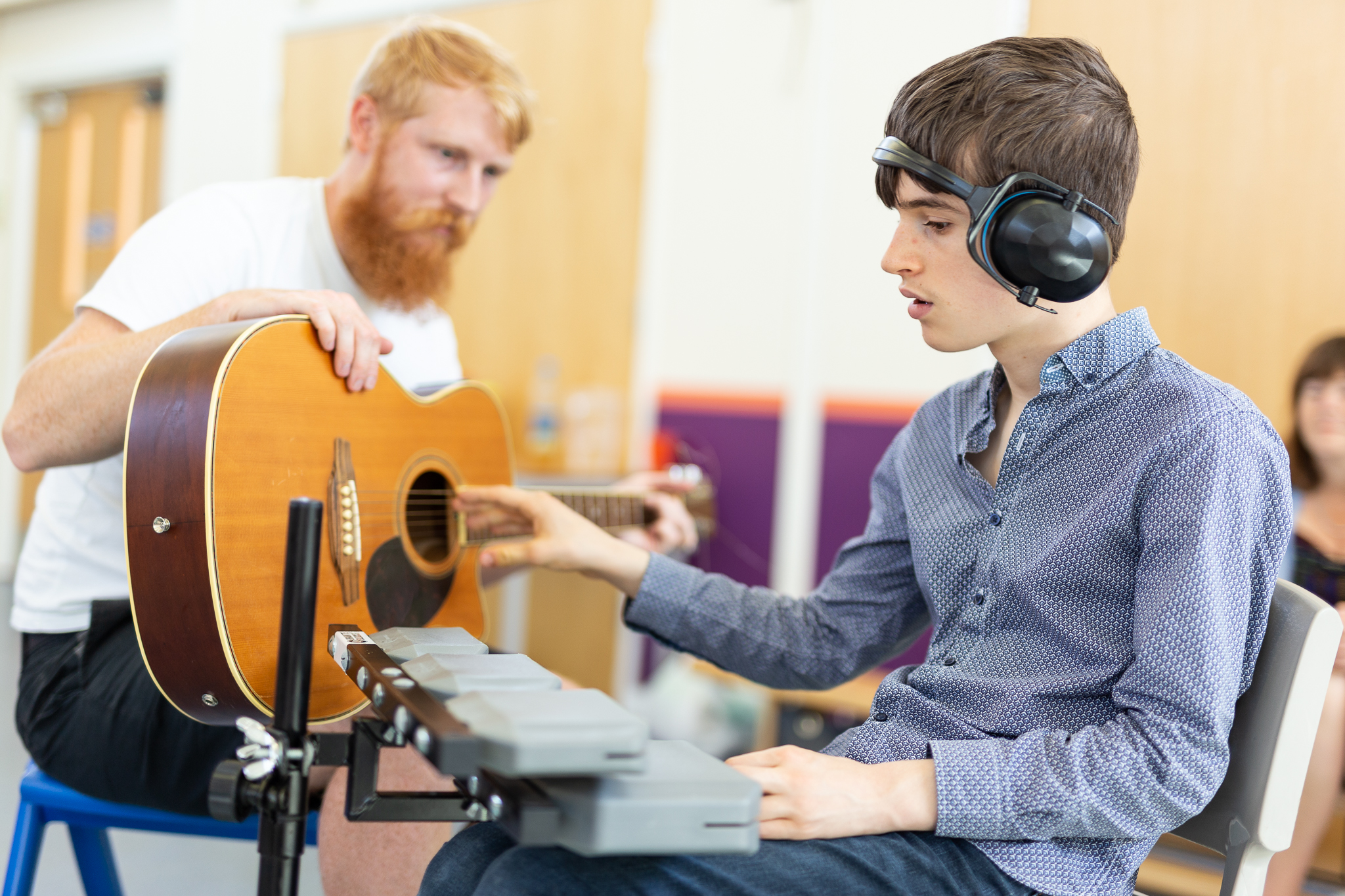 younger performer with tutor on guitar