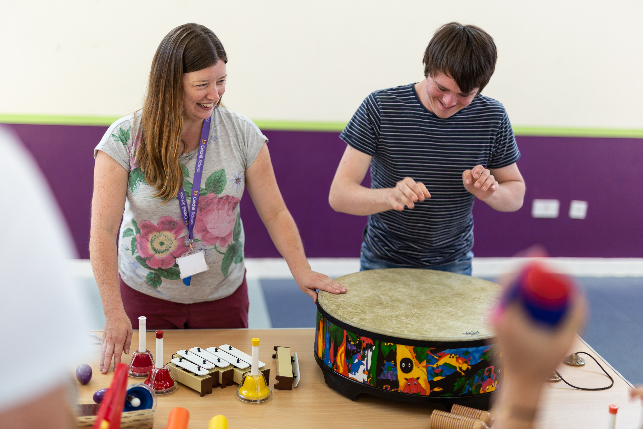 Younger performer learning to play the drum with tutor